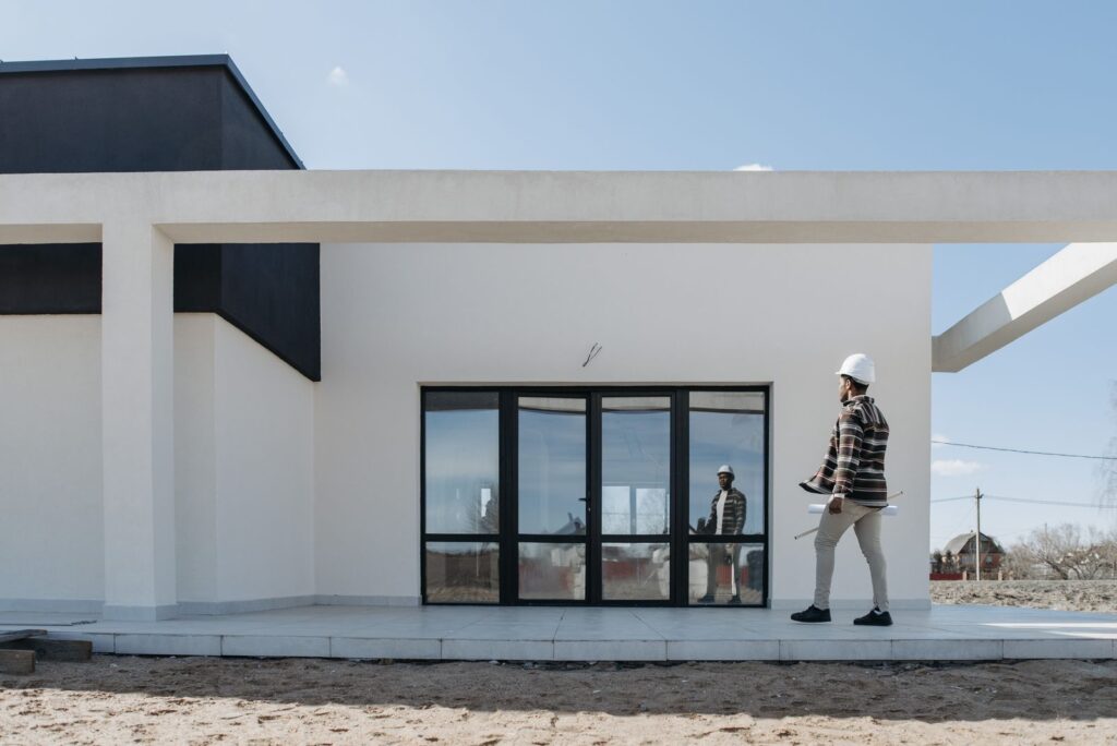 Engenheiro com capacete observando a fachada de uma casa nova