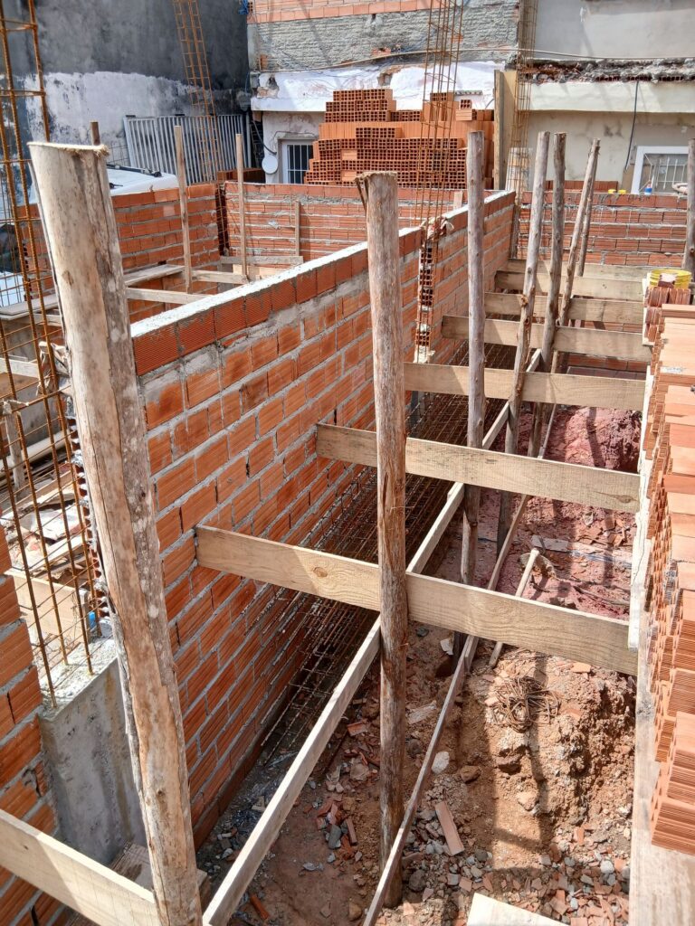 Obra em alvenaria com paredes de tijolos e escoras de madeira